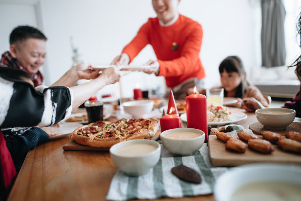 快乐的亚洲多代家庭一起庆祝圣诞节，在圣诞节聚会期间在家里传递和分享食物图片下载