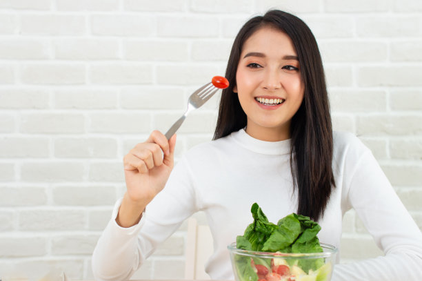 亚洲美女站在门口，手里拿着番茄叉，手里拿着沙拉碗。图片下载