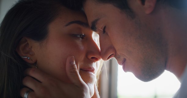 这对年轻情侣的真实照片是在一个阳光明媚的清晨在卧室里接吻。图片下载