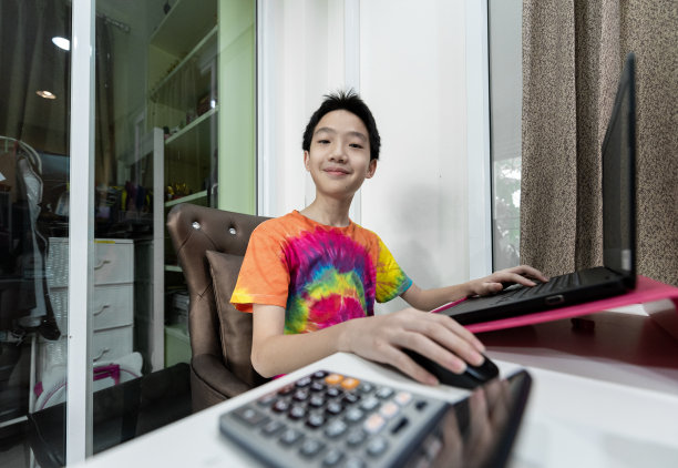 一个亚洲可爱的男孩在家里学习在线课程，社交距离，隔离和自我隔离。图片下载