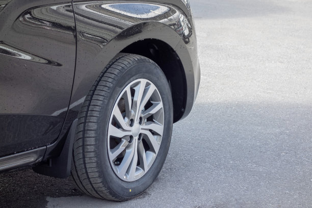 前轮上的轮辋特写在一个新的灰色跨界雨滴后。潮湿的人行道上。图片下载