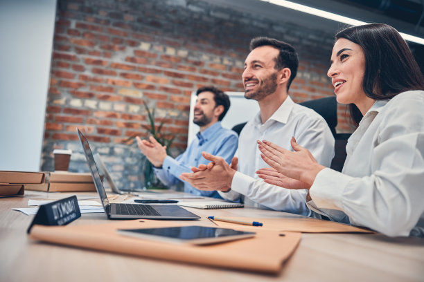 成功的同事坐在办公桌前使用电脑图片下载