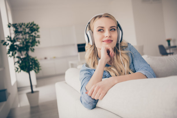 家庭漂亮迷人的金发女士放松的照片坐在舒适的沙发呆在家里，靠在手上听凉爽的耳机，梦想家隔离时间客厅室内图片下载