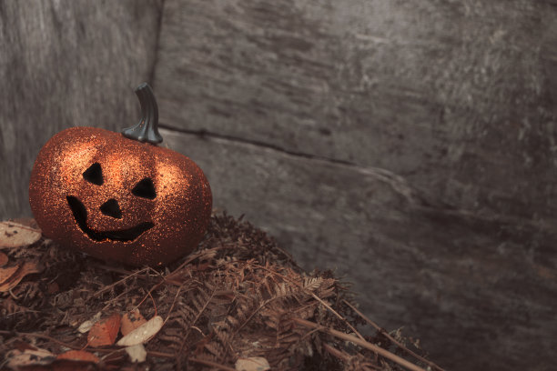 闪闪发光的万圣节南瓜在秋天的树叶上木制的背景。季节性的照片与空间为您的文本图片下载