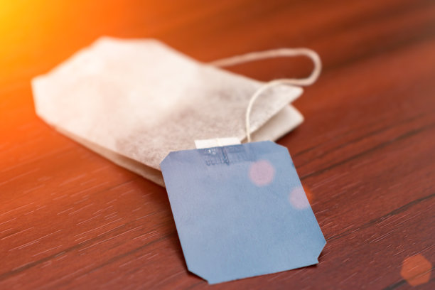 阳光下，桌上放着一个贴着标签的茶包图片下载