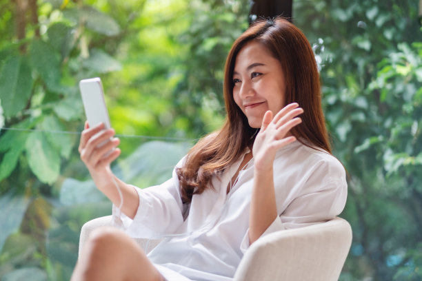 一位美丽的亚洲女子在家里用手机进行视频通话时挥手示意图片下载