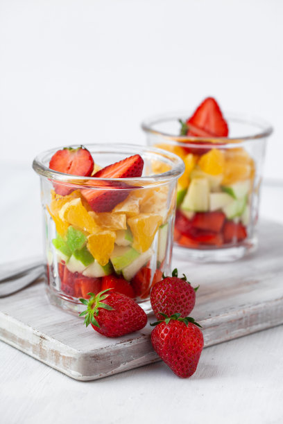 健康食品理念，清洁饮食。低卡路里的彩色甜夏日甜点。自制简单的水果沙拉，理想的早餐。橙、苹果、草莓。白色木质背景的文本复制空间图片下载
