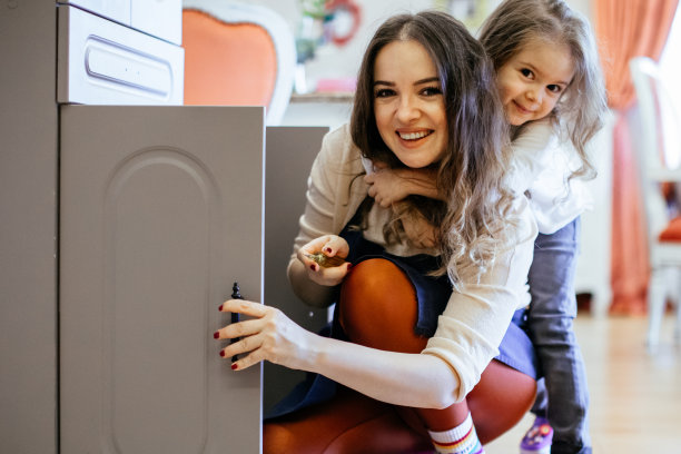 美丽年轻的母亲和女儿在家里组装木橱柜图片下载