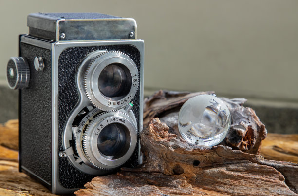复古的两镜头照片相机与玻璃水晶球在木制背景。图片下载