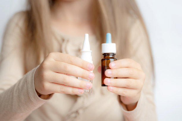 小女孩手里拿着两种滴鼻剂。儿童流鼻涕。过敏,图片下载