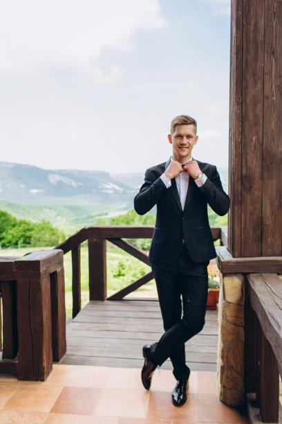 年轻的新郎穿着婚纱，背景是群山。图片下载