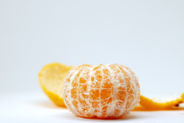 多汁的橘子剥落在白色的背景。亮橙色的柑橘类水果。整个没有皮的橘子。图片下载