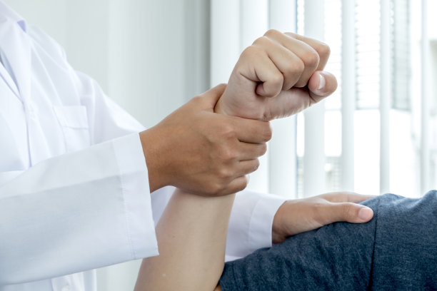 女性理疗师协助男性肘部损伤患者在康复中心检查患者。物理治疗的概念图片下载