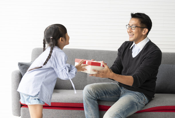 亚裔女儿给父亲送礼物。概念惊喜礼物盒父亲节。图片下载