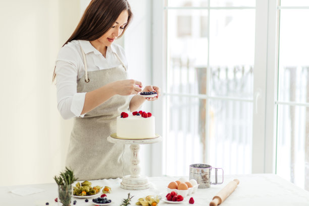 讨人喜欢的糖果师傅用蓝莓和覆盆子来装饰蛋糕图片下载
