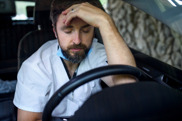 疲惫不堪的医生坐在车后，长时间和困难的轮班。图片下载
