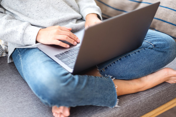 坐在家里沙发上使用和工作笔记本电脑的妇女图片下载