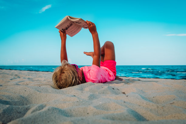 小女孩在沙滩上看书，孩子在假期里学习图片下载