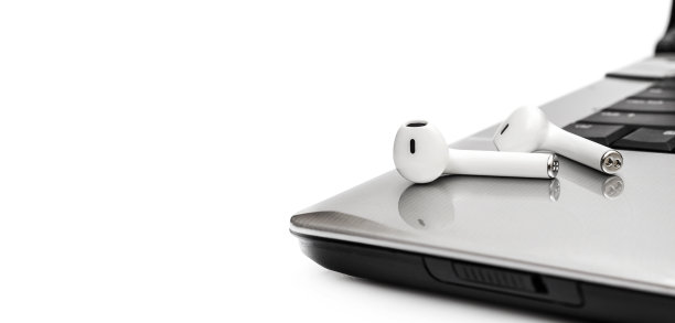 蓝牙耳机在笔记本电脑上隔离白色。关闭了。素材图片