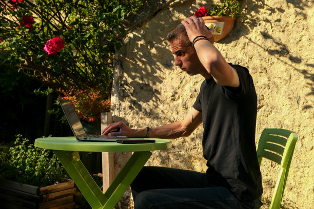 一个焦虑、紧张、过度劳累的男人，在自家花园里的笔记本电脑上工作。图片下载