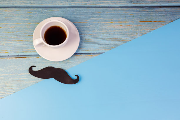 父亲节理念快乐。一张黑色的小胡子纸和一杯孤立在蓝色背景上的咖啡。图片下载