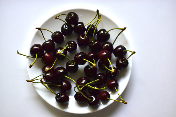 白色盘子里放着成熟的红色水果和美味的樱桃图片下载