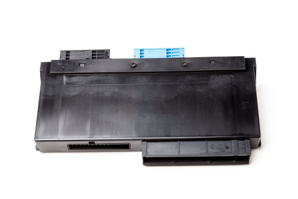 从白色隔离背景的汽车上拆卸下来的备件是一个用于更换和维修的黑色塑料电子控制单元。备件目录。图片下载