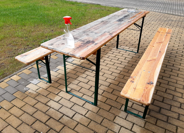 木制的桌子上没有长凳，只有桌子上有防冠状病毒的消毒喷雾，桌子下面有米色的连锁瓷砖图片下载