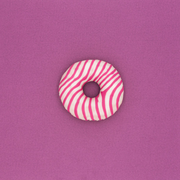 粉色背景上点缀着糖霜和糖果的美味甜甜圈。广场照明背景。图片下载