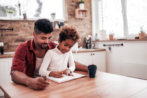 爸爸看着他可爱的女儿在家里写字和学习。图片下载