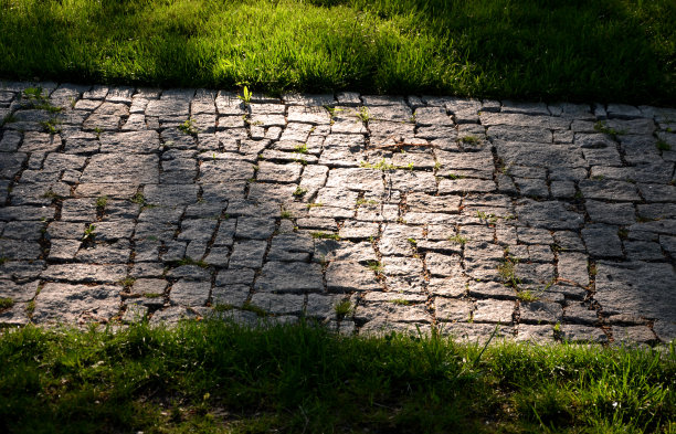 花岗岩铺砌不规则分段的碎石路，公园周围有绿色草坪灰色的人行步道图片下载