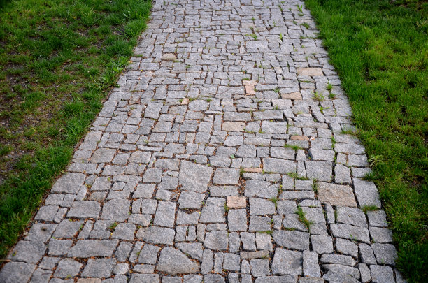 花岗岩铺砌不规则分段的碎石路，公园周围有绿色草坪灰色的人行步道图片下载