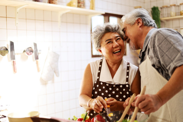 幸福的老夫妇有乐趣在厨房与健康的食物，从家里工作。新型冠状病毒肺炎素材图片