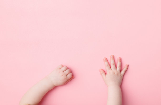小女孩的手放在浅粉色的桌子背景上。柔和的颜色。特写镜头。视角拍摄。自顶向下的观点。图片下载