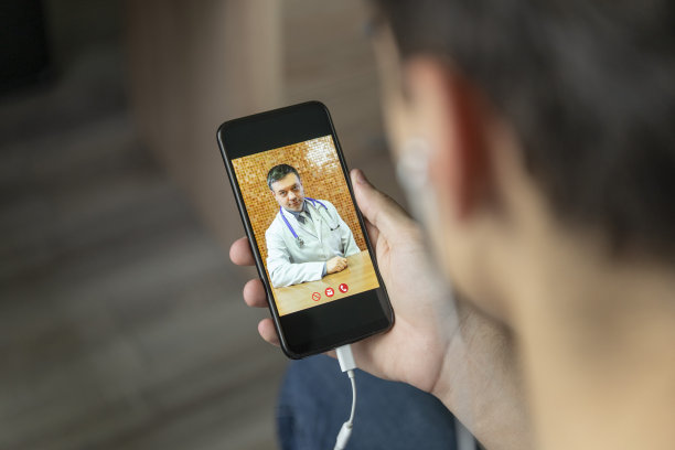 男子在家用智能手机和医生视频聊天。医疗保健在线咨询概念图片下载