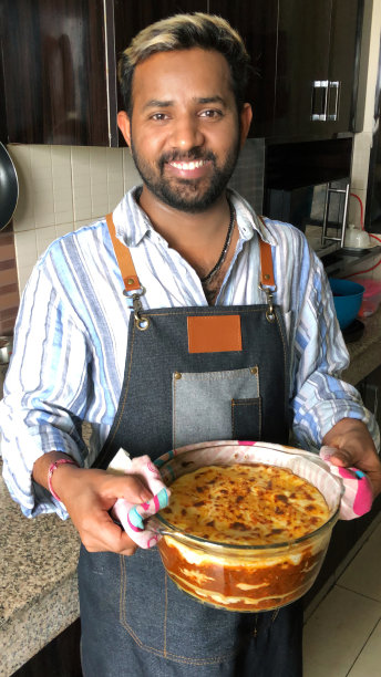 英俊的印度男人拿着玻璃盘子里的千面，男人戴着皮围裙，看着照相机，印度。印度男子身穿蓝白条纹衬衫，凌乱的金色头发梳在脑后图片下载