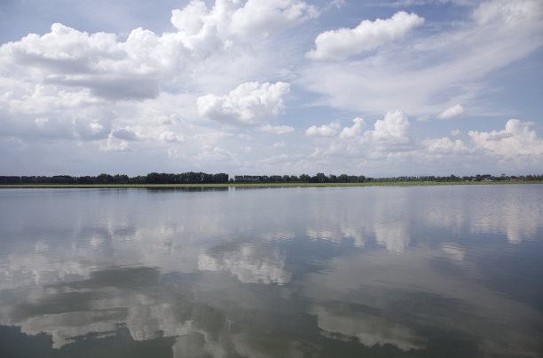 湖面上倒映着多云的天空，远处还有树木图片下载