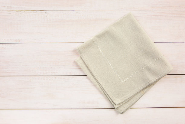 米色折叠毛巾，布上木制背景俯视图。食品广告显示。图片下载