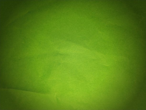 一张皱巴巴的绿色厚纸。一方面，光照更有力量。纸纹理。明亮的绿色变成浅绿色。渐晕图片下载