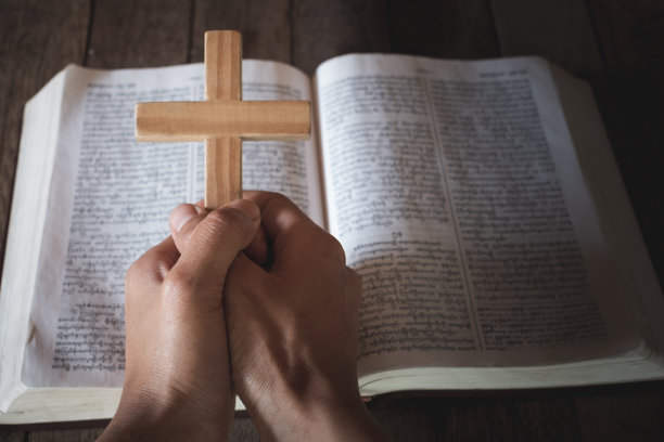 人手中的十字架落在圣经上。研究基督教，基督教，天主教，上帝，天堂，天堂，上帝或上帝的概念。上帝帮助忏悔，祈祷复活节，天主教大斋节。图片下载