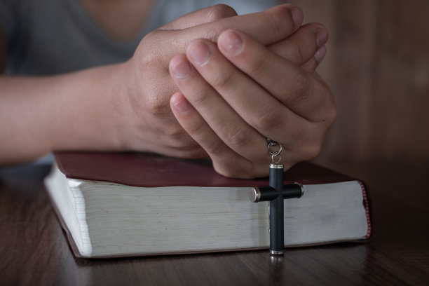 人手中的十字架落在圣经上。研究基督教，基督教，天主教，上帝，天堂，天堂，上帝或上帝的概念。上帝帮助忏悔，祈祷复活节，天主教大斋节。图片下载