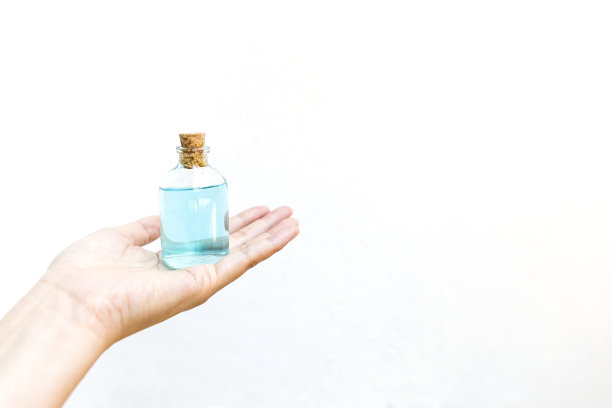 女孩手握玻璃瓶中的乙醇酒精，白色背景图片下载