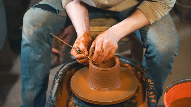 陶工在车间里用粘土在轮子上工作。图片下载