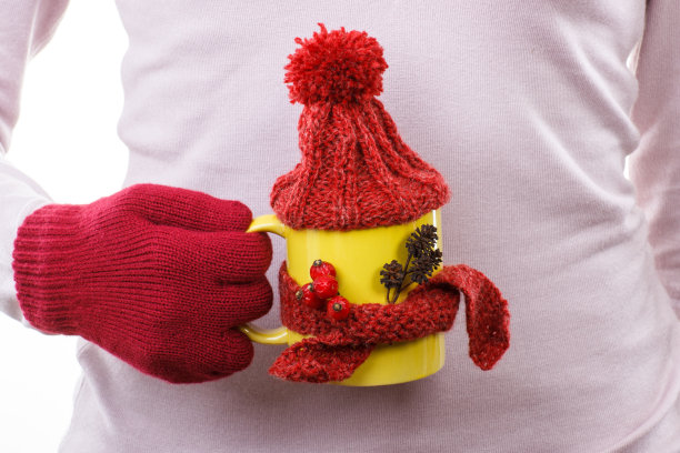 手戴手套的女人拿着一杯茶，羊毛围巾和帽子图片下载