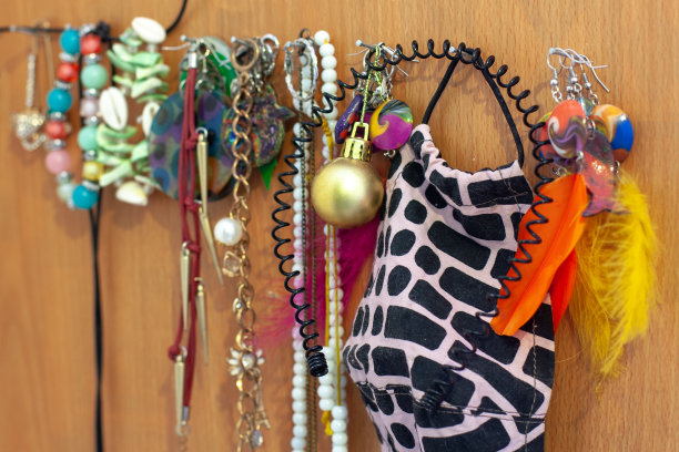 自制的面具和女性小饰品挂在钉子上。青少年的珠宝，珠子，手镯和羽毛耳环。选择性聚焦于掩模。水平的。图片下载