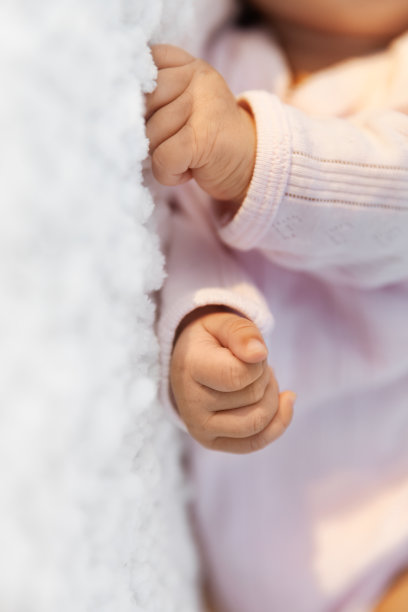 新生女婴紧握在白色毯子上，这是婴儿和产妇的概念图片下载