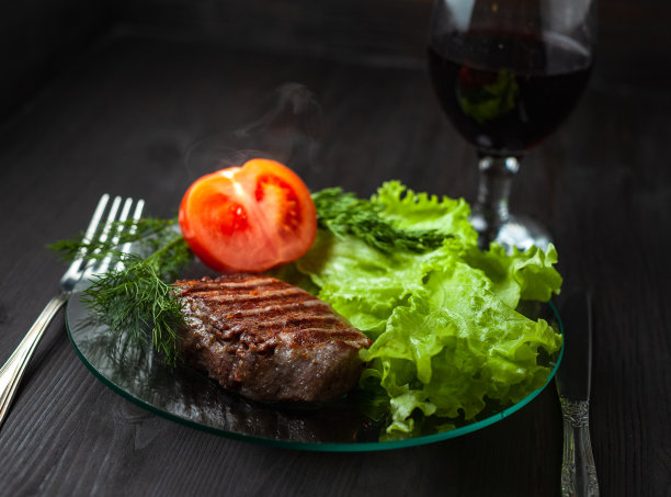 热牛排配菜，蔬菜和一杯葡萄酒图片下载
