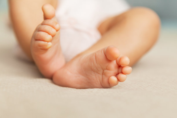 新生儿的脚上的米色背景，孕妇和儿童的概念图片下载