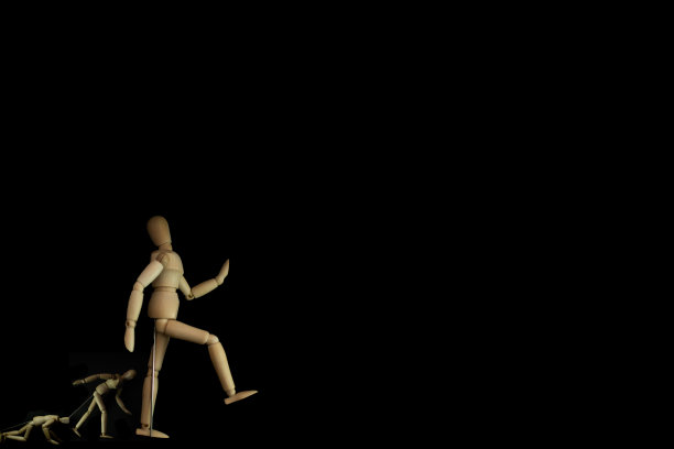 木制人体模型在黑色背景上行走图片下载