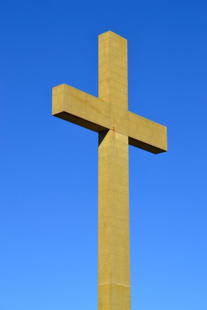 在钴蓝色晴朗的天空下孤立地敲击着巨大的混凝土十字架或十字架图片下载
